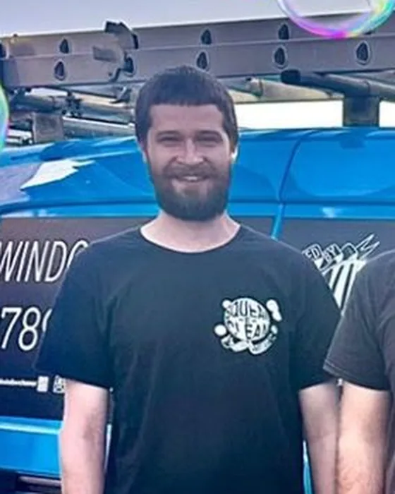 Tom in a black Squeak-E-Clean T-shirt in front of the blue van