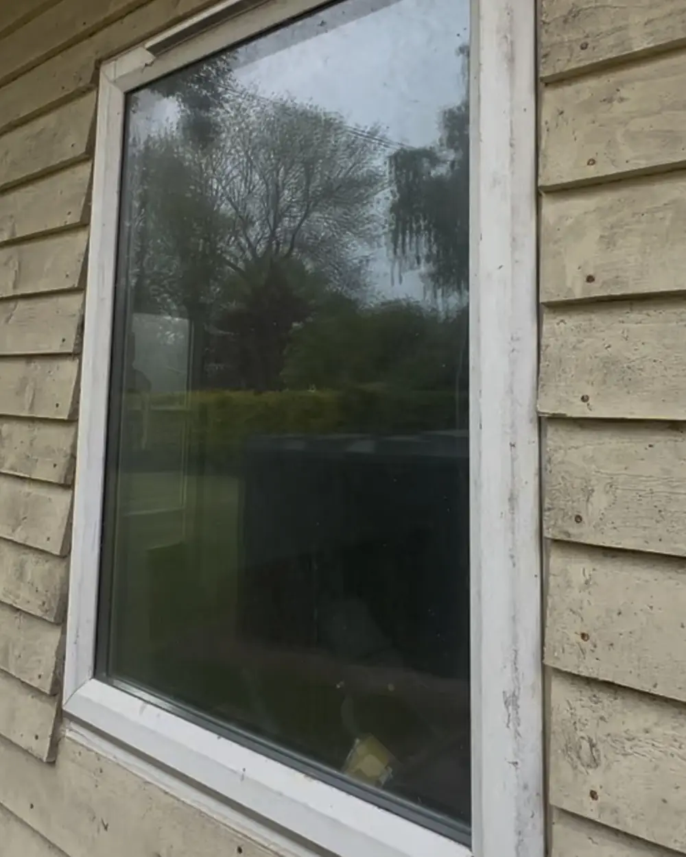 Before: a white window in timber cladding with spotty glass and a dirty frame