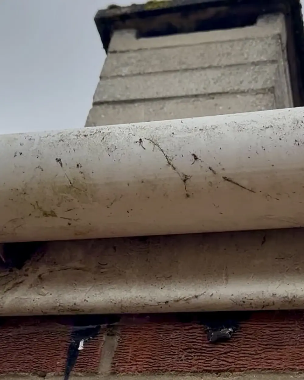 Before: a dirty, stained white gutter and fascia below a chimney